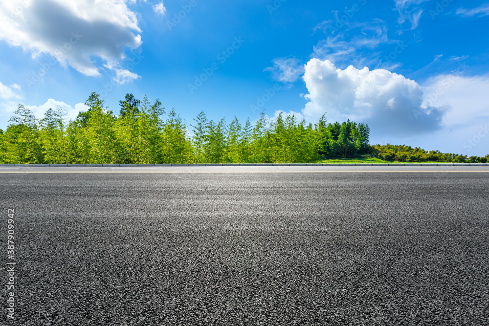 Asphalt road and green bamboo with mountain natural scenery in Hangzhou on a sunny day.