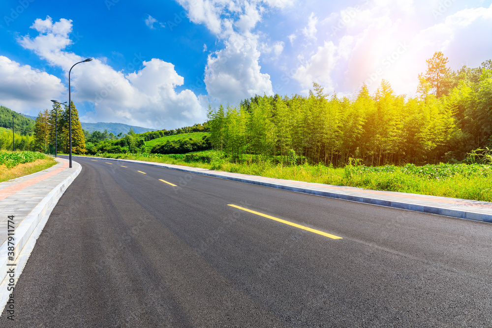 Asphalt road and green plants with mountain natural scenery in Hangzhou on a sunny day.