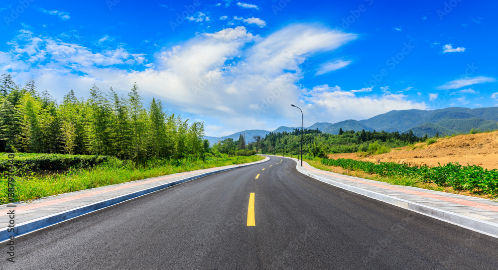 Countryside asphalt road and green plants with mountain natural scenery in Hangzhou on a sunny day.