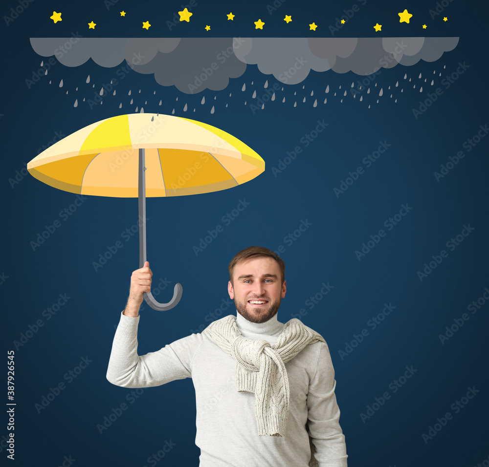 Handsome young man holding umbrella on dark color background with drawn rainy clouds