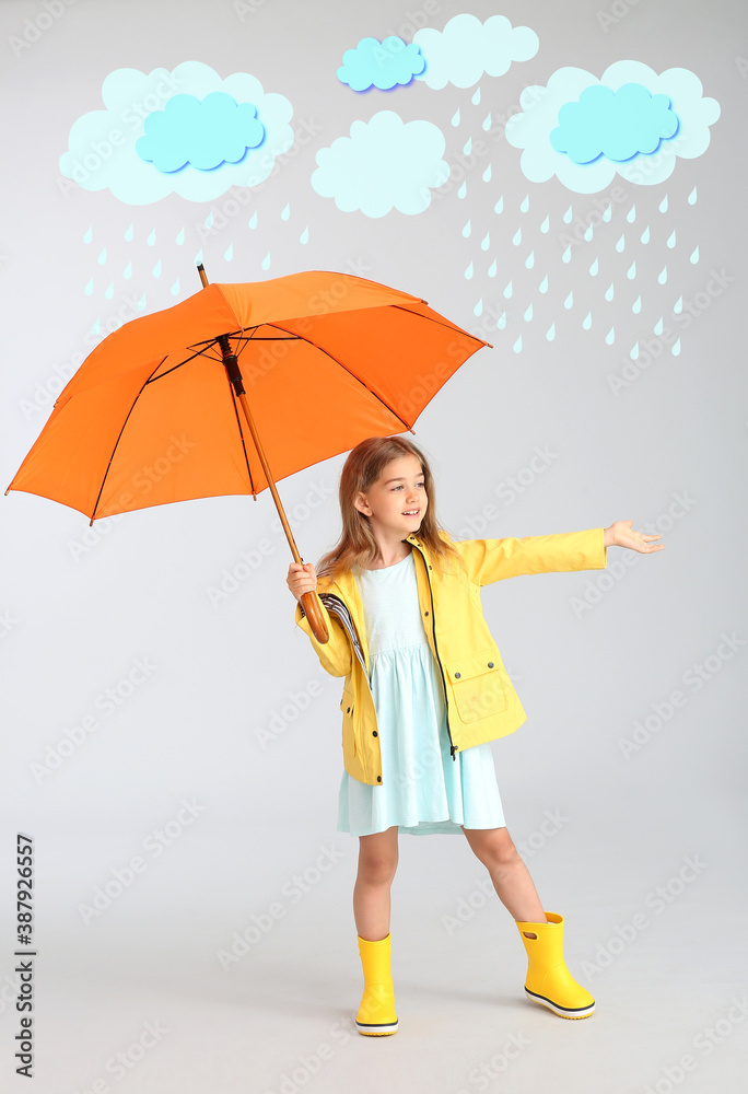 Cute little girl holding umbrella on grey background with drawn rainy clouds