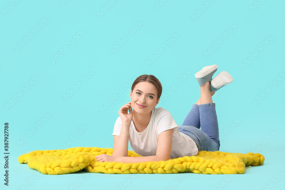 Happy young woman with warm plaid on color background