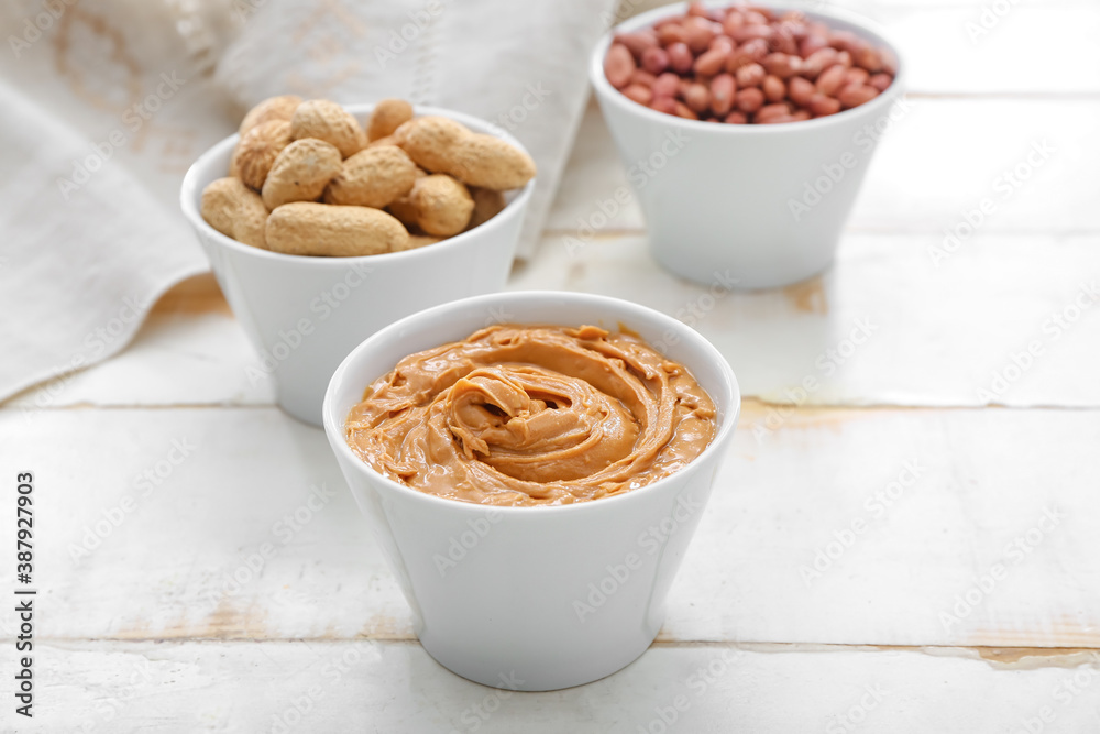 Bowls with tasty peanuts and butter on table