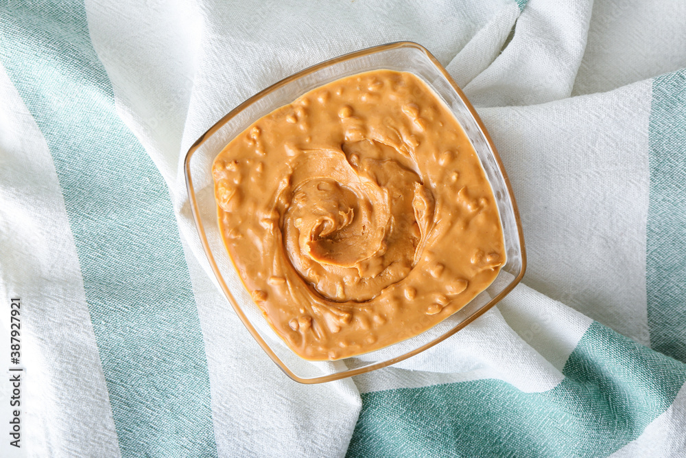 Bowl with tasty peanut butter on table