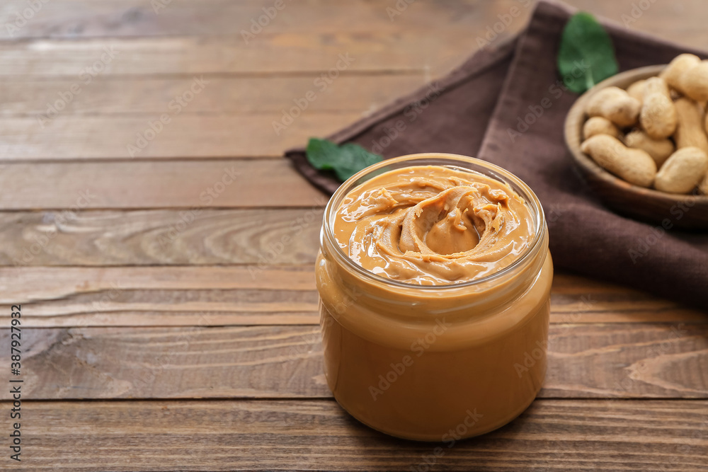 Jar with tasty peanut butter on table