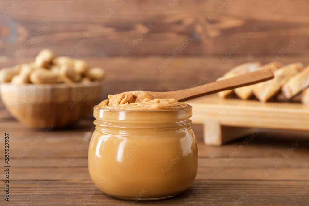 Jar with tasty peanut butter on table