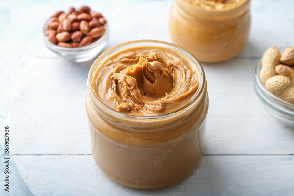 Jar with tasty peanut butter on table