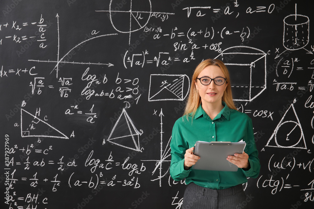 Mature maths teacher near blackboard in classroom