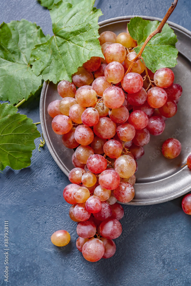 Plate with sweet ripe grapes on table