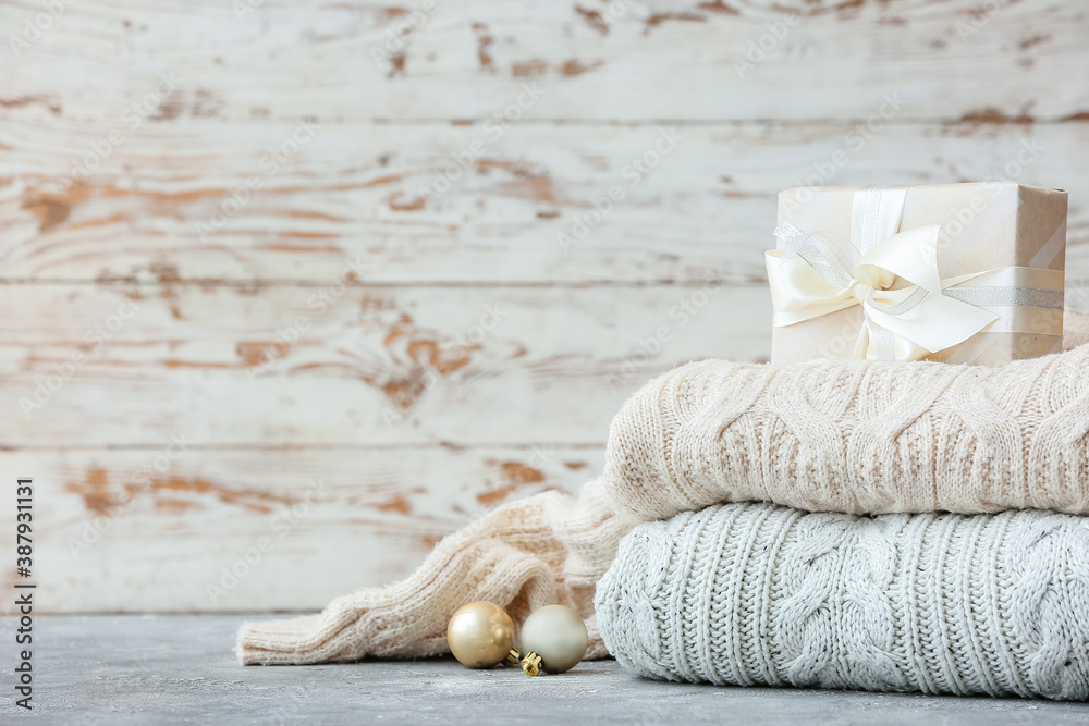 Stylish Christmas clothes with gift on table