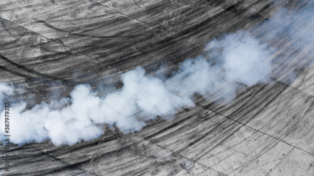 Black tire marks and white smoke on asphalt race track, Road dust cloud from driving car, Combustion