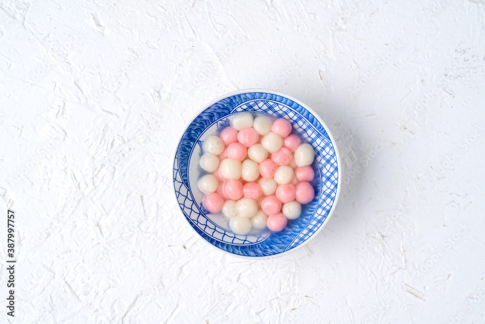 Top view of red and white tangyuan in blue bowl on white background for Winter solstice.