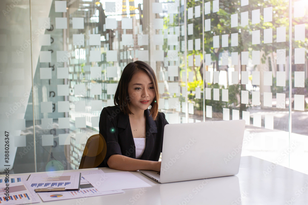 Portrait of a happy face Asian woman sitting at home working on a laptop while sitting on a desk. To