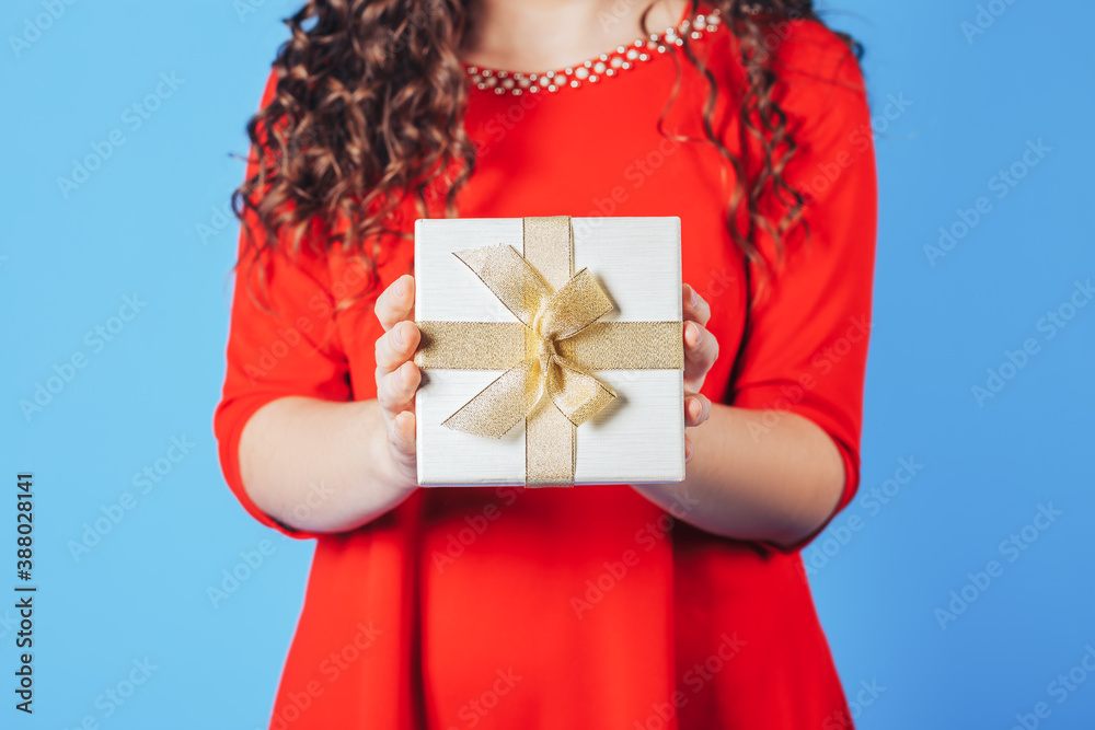 Beautiful woman in red dress on a blue background holding box with a gift in her hands