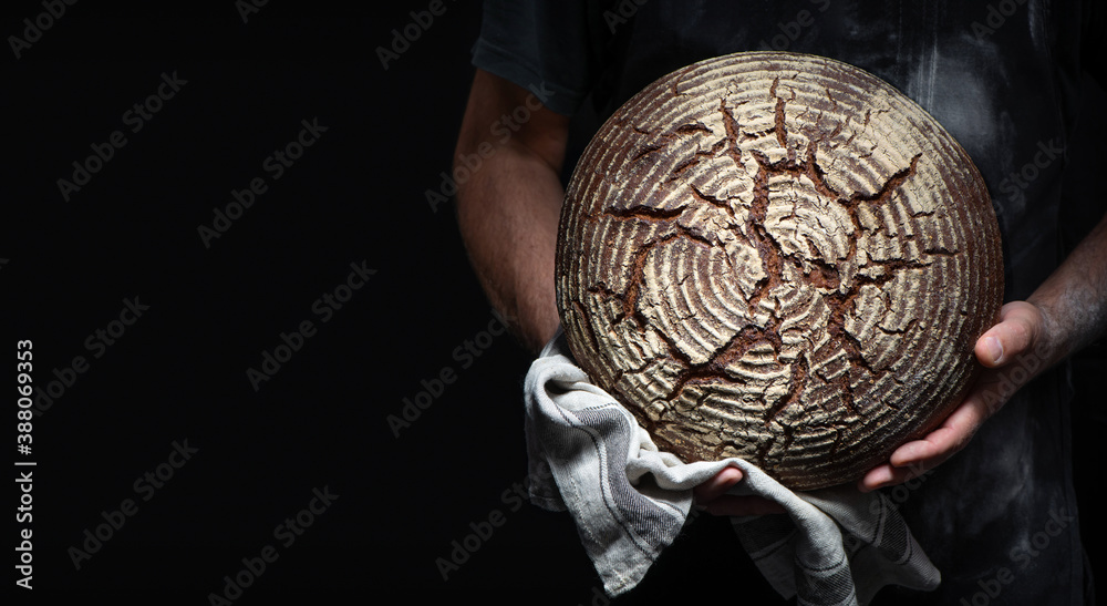 Bakers hands holding and presenting fresh baked loaf of bread