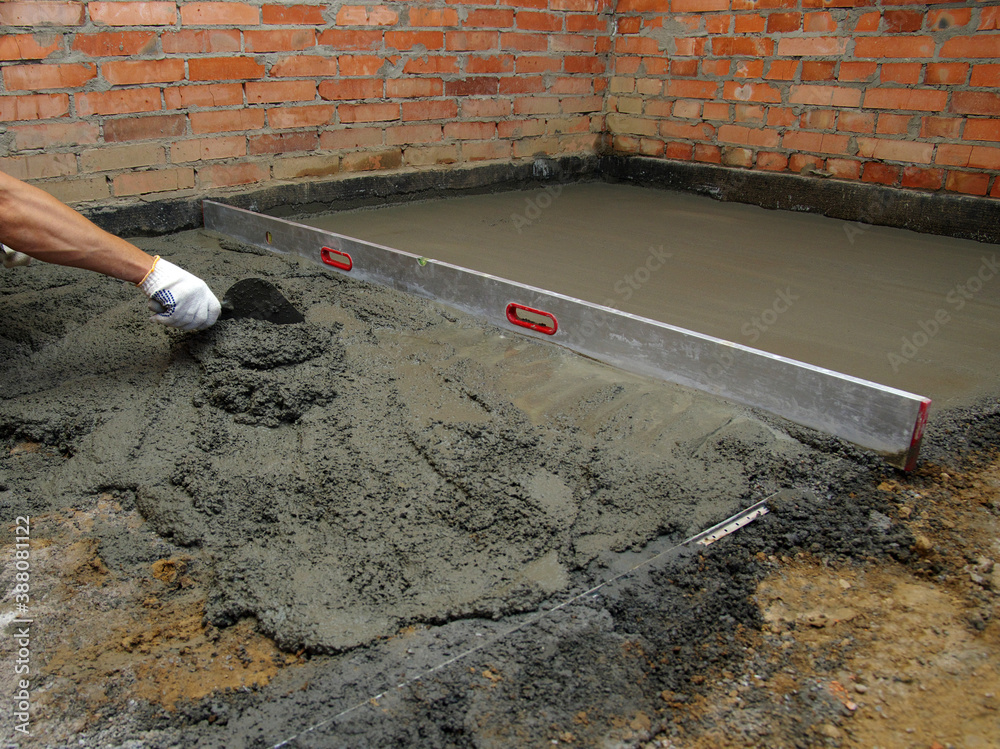 worker screeding indoor cement floor with screed