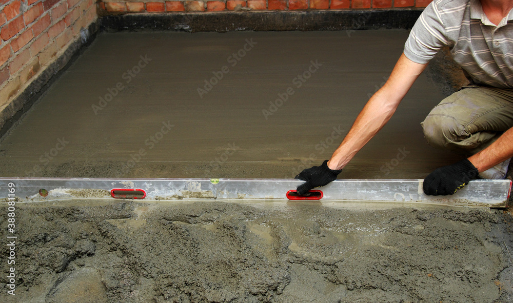 worker screeding indoor cement floor with screed