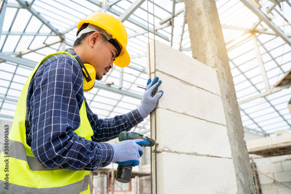 Closeup of a construction worker hands using a drill on a construction site.