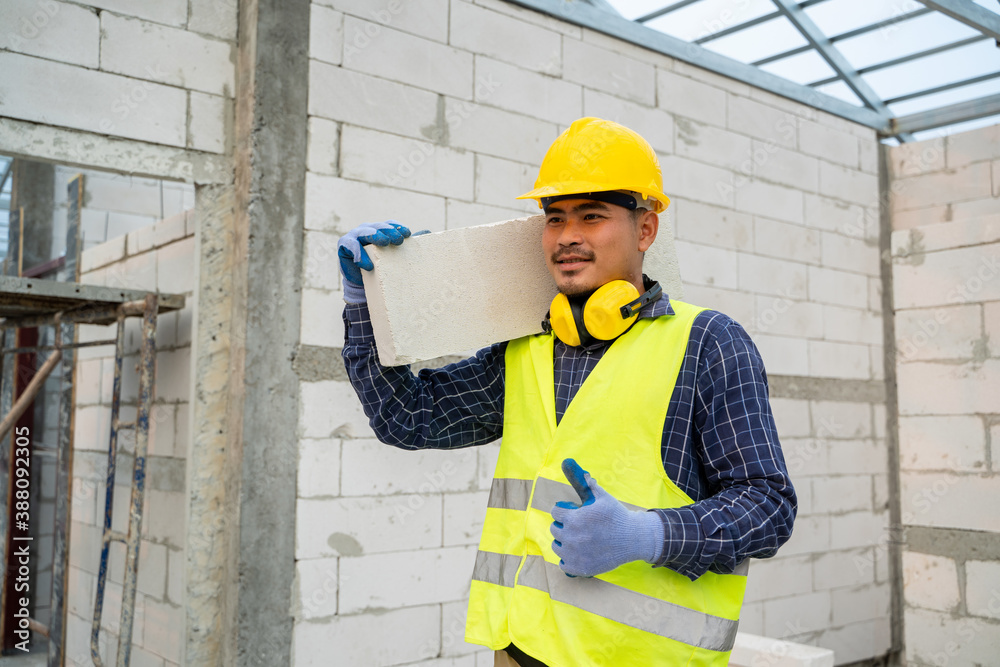 Masonry worker make concrete wall by cement block and plaster in the new house under construction.