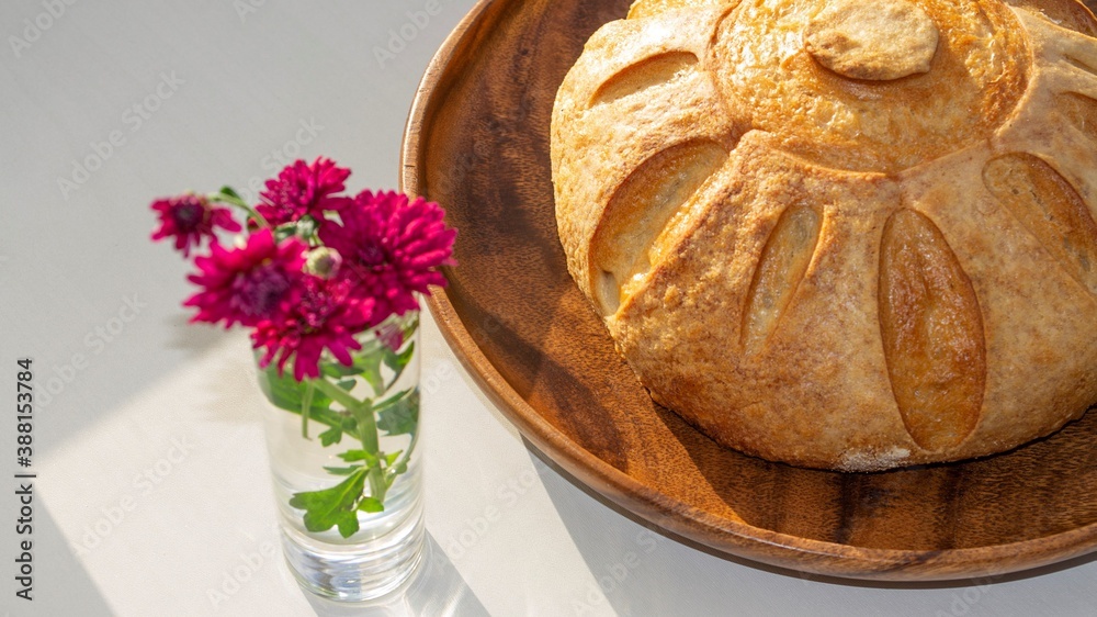 Artistic composition in the bright rays of the sun. Homemade whole grain bread (french loaf) on a wo