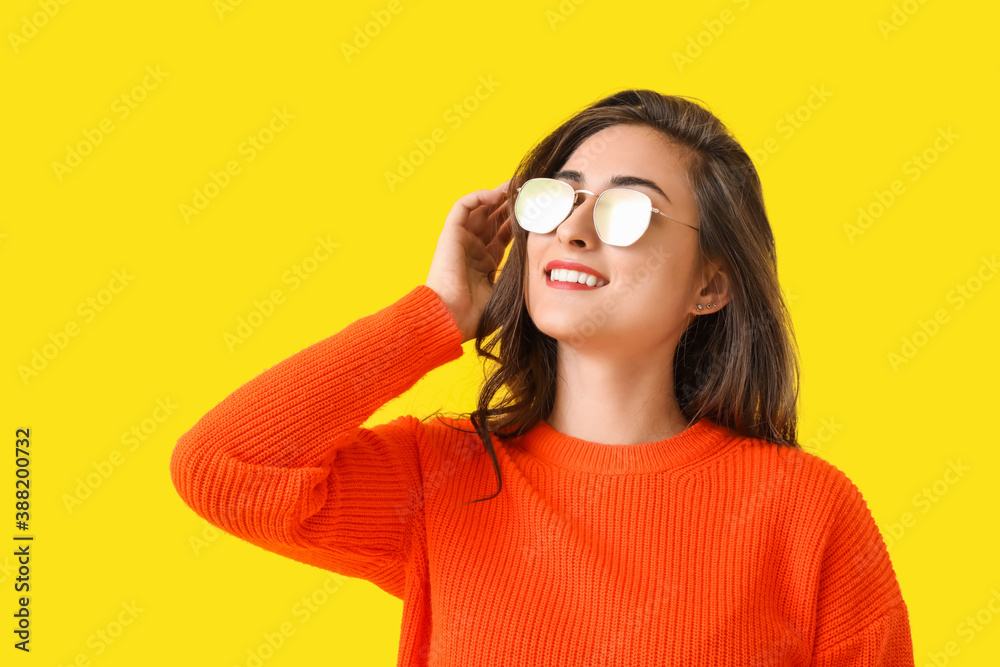 Stylish young woman in autumn clothes on color background