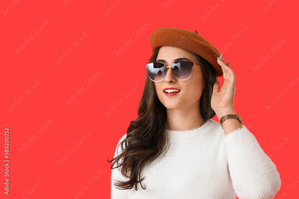 Stylish young woman in autumn clothes on color background