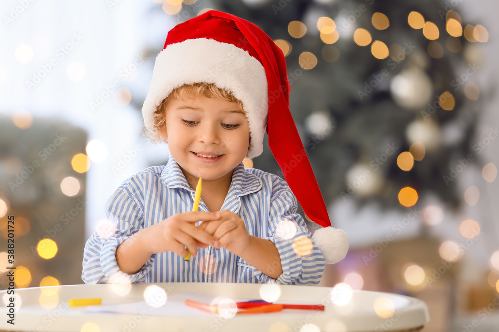 Cute little child writing letter to Santa at home