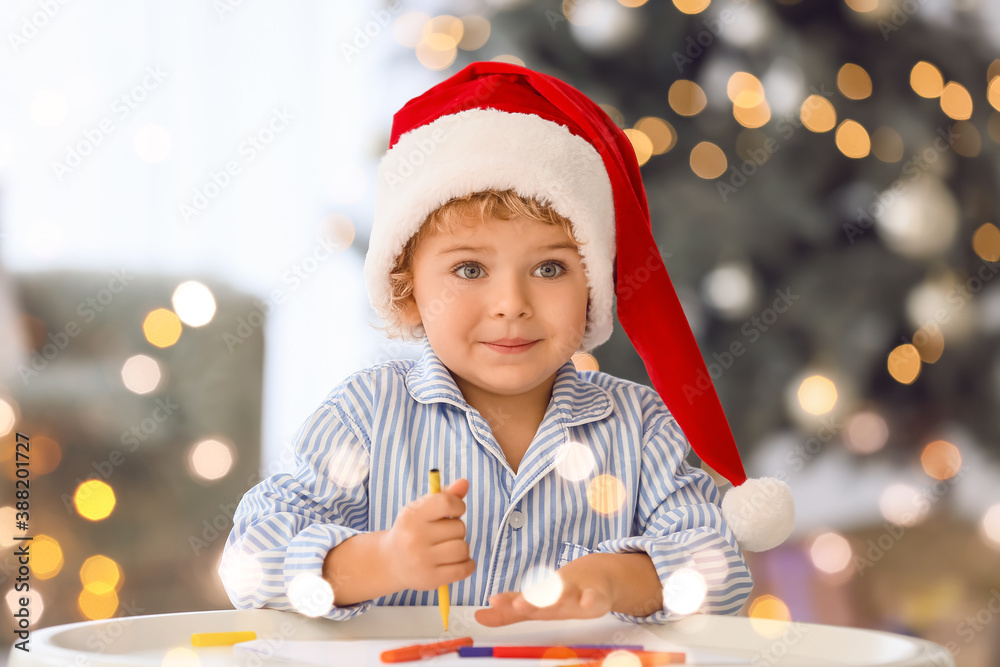 Cute little child writing letter to Santa at home