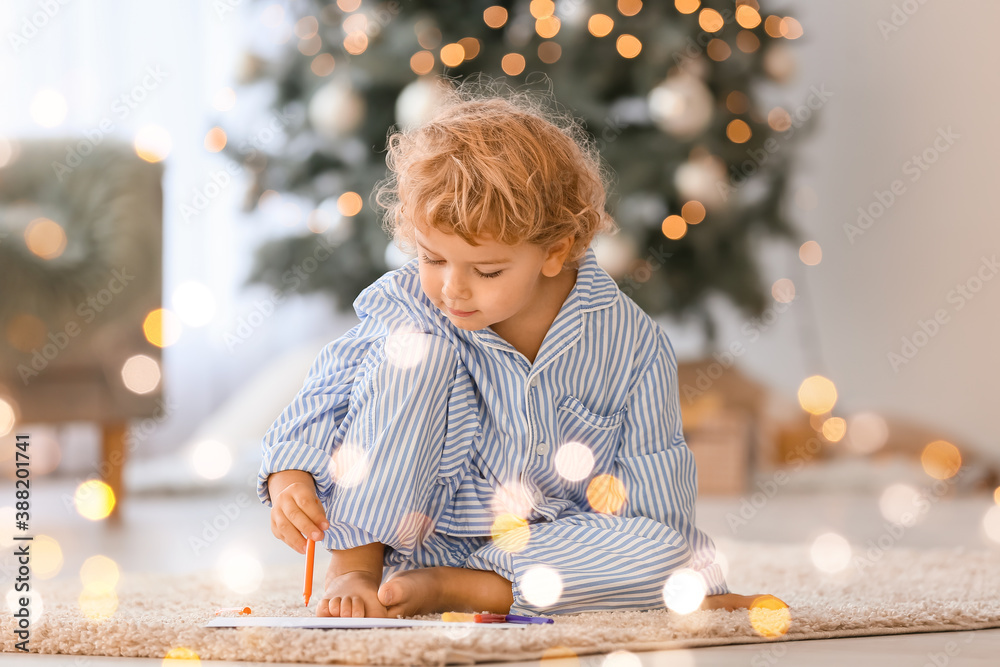 Cute little child writing letter to Santa at home