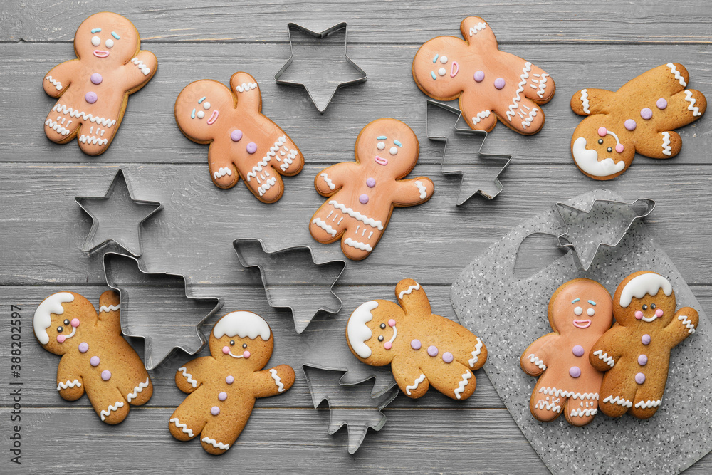 Tasty gingerbread cookies and cutters on wooden background