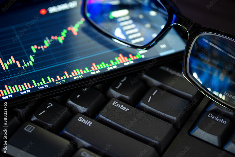 Stock market chart screen on keyboard computer and eyeglasses, online investment concept