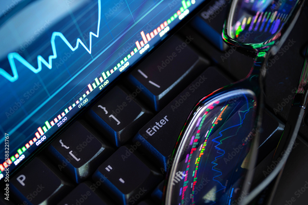 Stock market chart screen on keyboard computer and eyeglasses, online investment concept