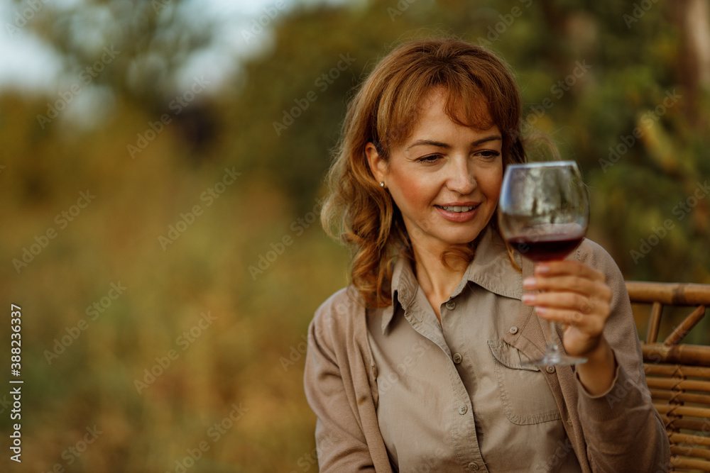 Woman trying red wine from her production of wine.