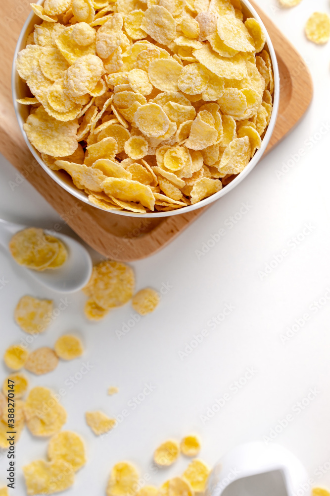 Top view of corn flakes bowl with milk on white background.