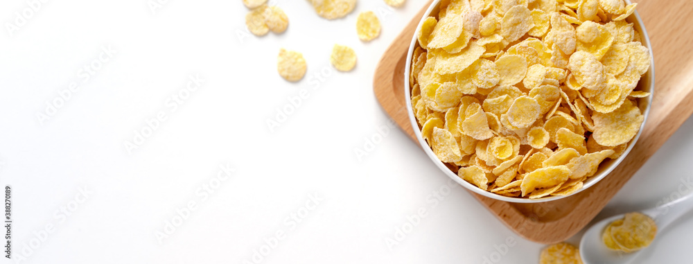 Top view of corn flakes bowl with milk on white background.