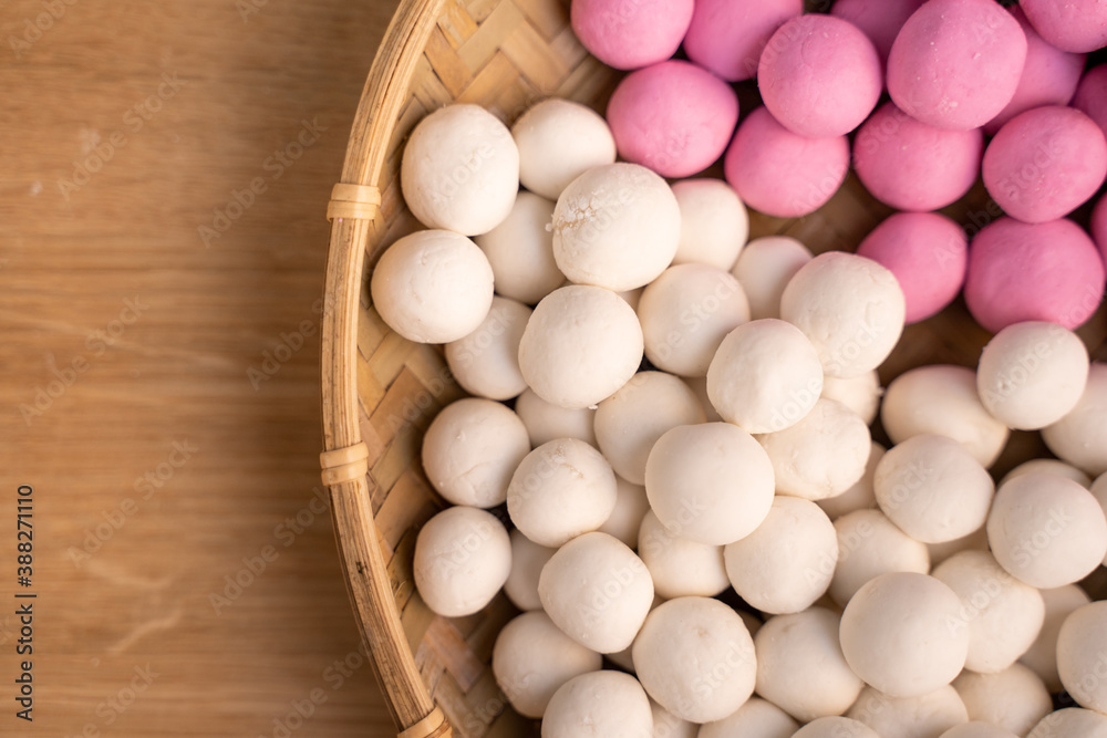 Raw little tangyuan in a sieve over wooden table.