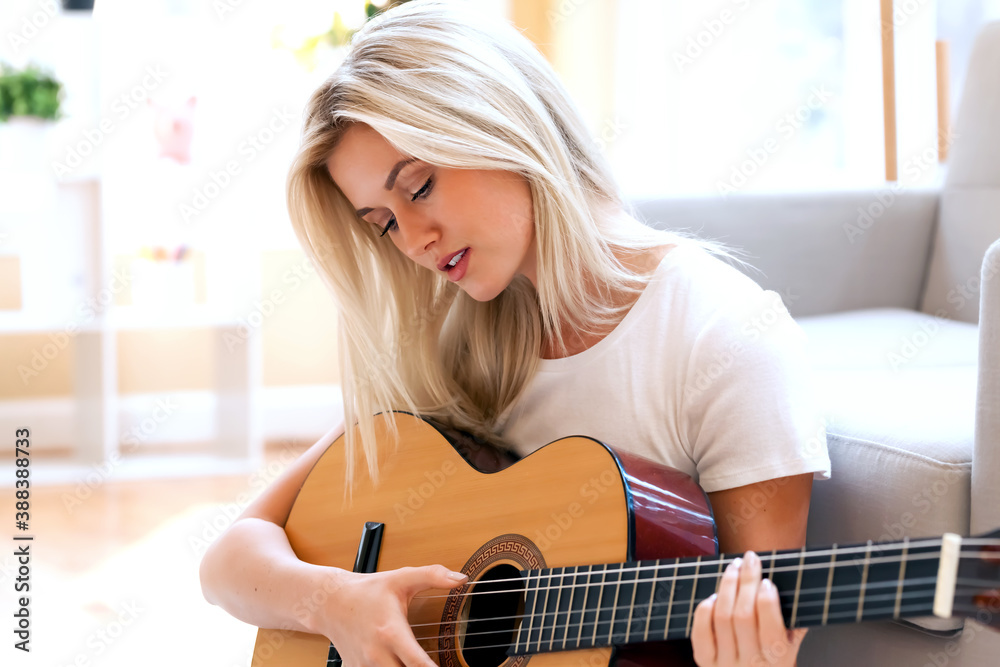 Young woman playing her guitar at home