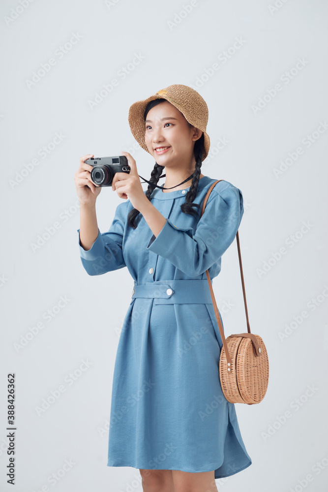 Portrait of a smiling young woman in summer hat standing with photo camera isolated over white backg