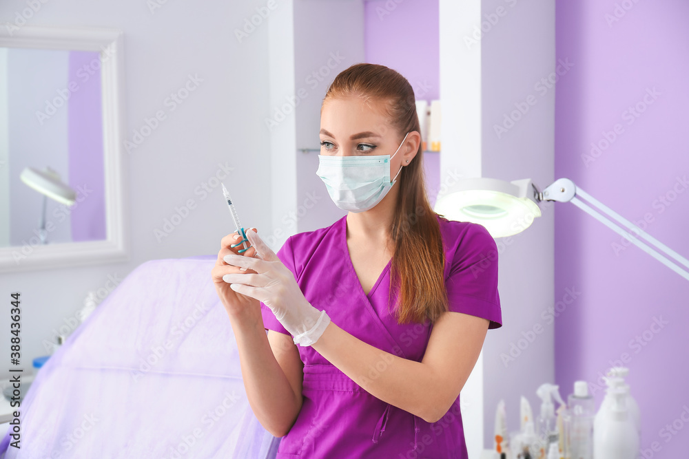 Professional beautician with syringe in modern clinic