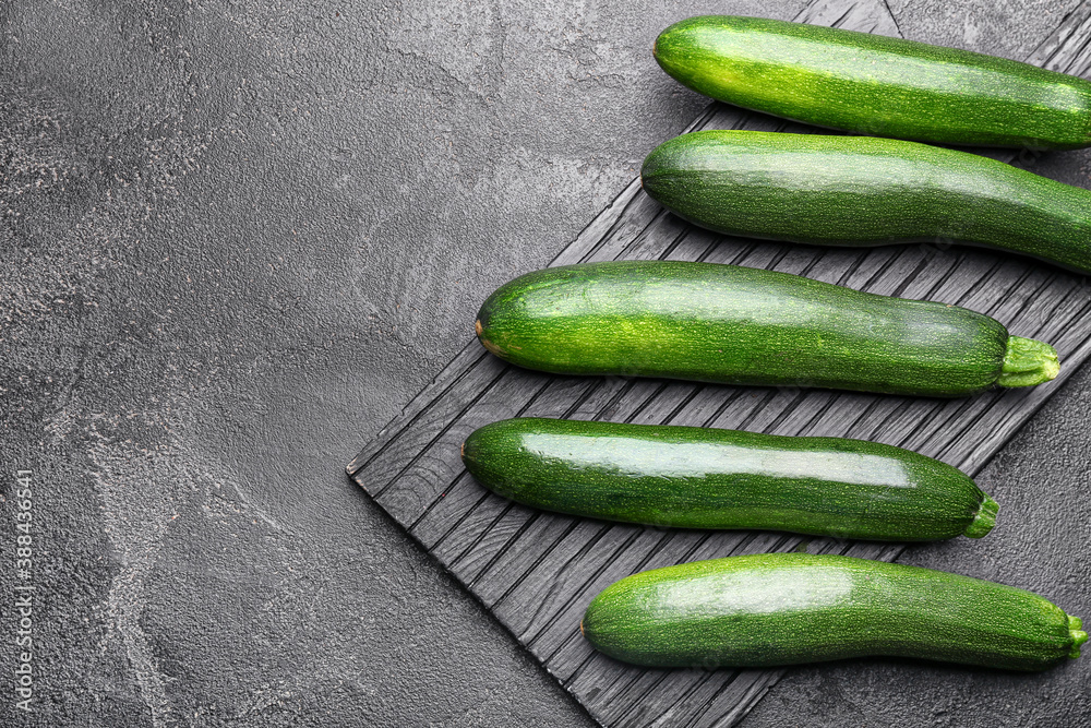 Board with fresh zucchini squashes on dark background