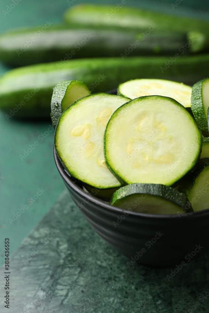 Bowl with fresh zucchini squashes on color background, closeup