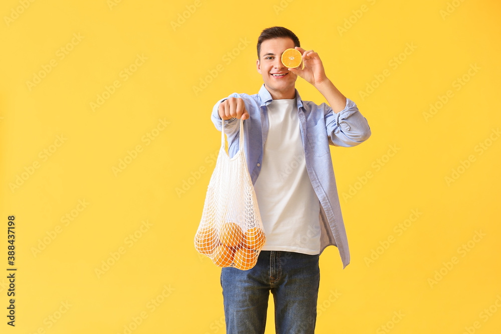 Handsome man with ripe oranges on color background