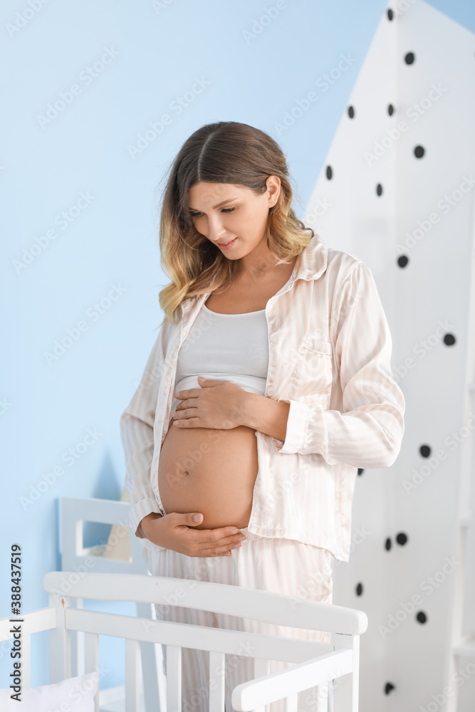 Beautiful pregnant woman near baby bed at home