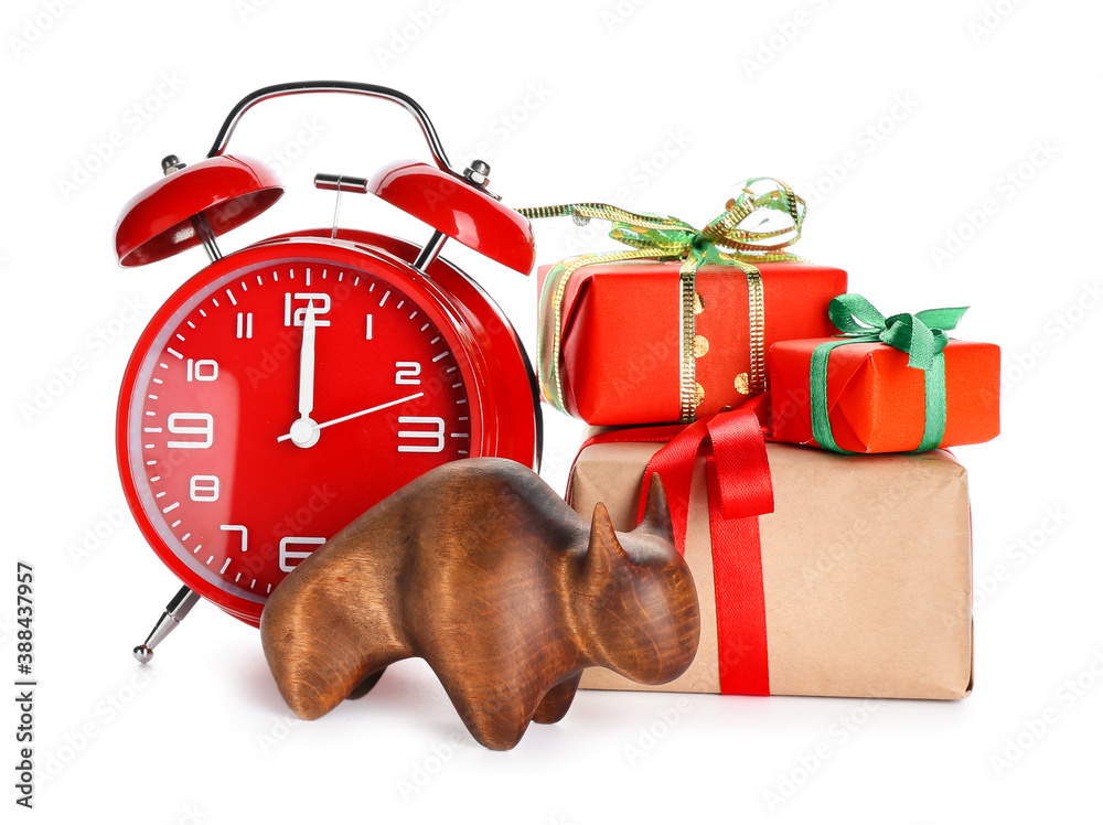 Figurine of bull, alarm clock and New Year gifts on white background