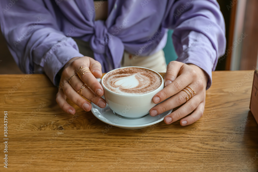 Woman drinking hot coffee in cafe, closeup