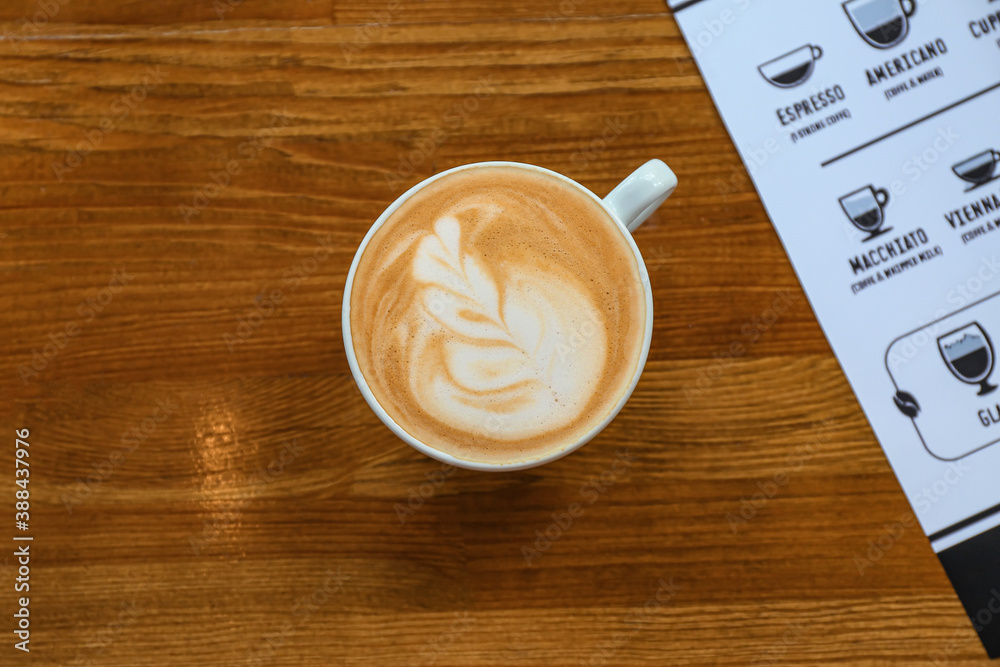 Cup of hot cappuccino on table in cafe