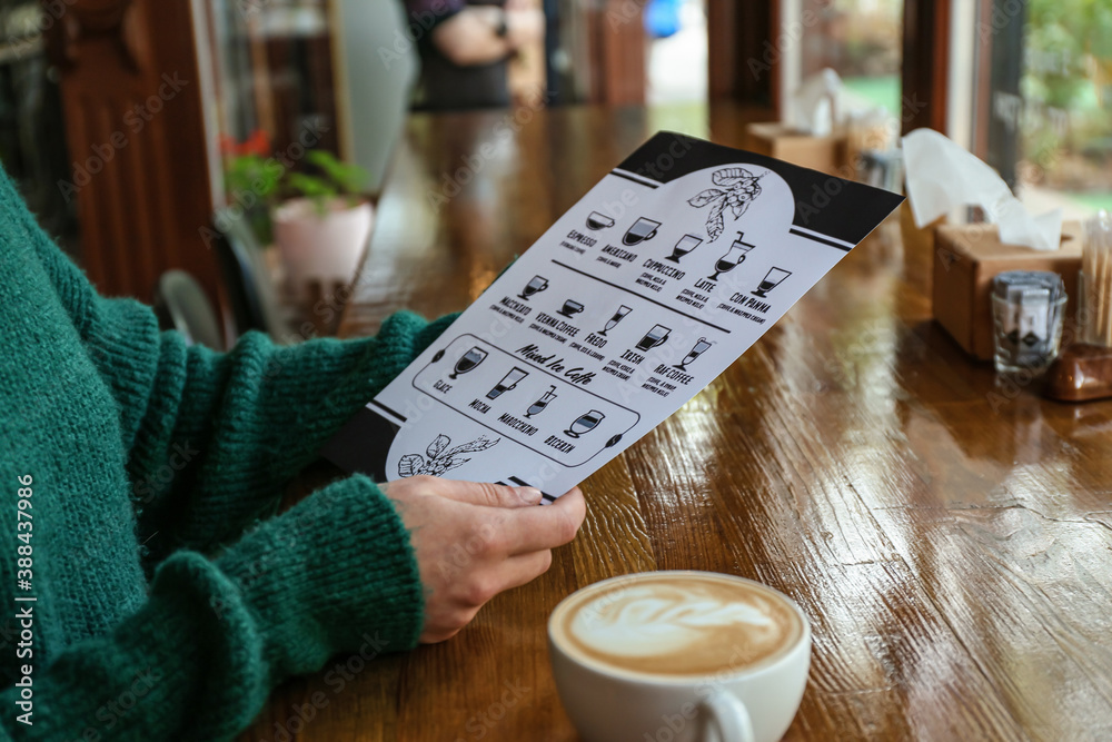 Woman with menu and cup of coffee in cafe