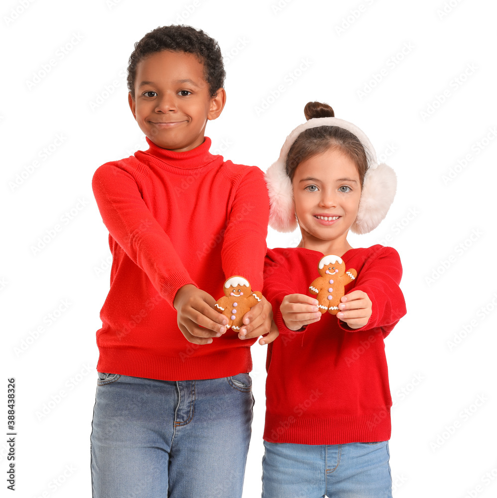 Cute children in winter clothes and with cookies on white background