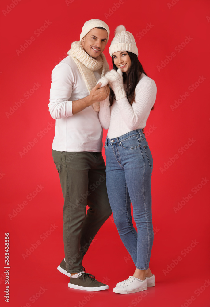 Young couple in winter clothes on color background