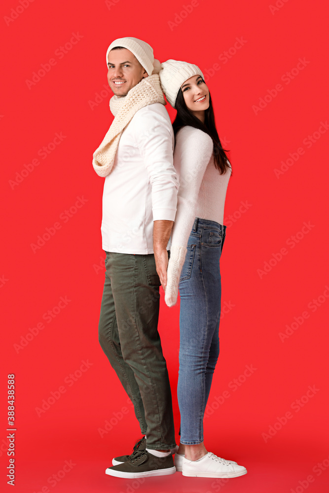 Young couple in winter clothes on color background